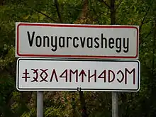 Ortstafel in lateinischer Schrift und Rovásírás