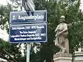Straßenschild 7.,&nbsp;Augustinplatz. Darunter Zusatztafel mit den biografischen Grunddaten des Namensgebers und der Namensgeberin, nach denen der Platz im Mai 2009 benannt wurde.