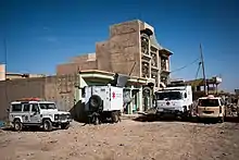 Die Cadus-Einsatzfahrzeuge und ein Anhänger des Mobile Hospitals vor einem mehrstöckigen Gebäude