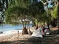 Touristen zelten am Strand bei den Fischerbooten