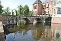 Blick auf Wassergraben und Bogenbrücke