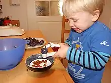 Kind beim Entkernen einer Zwetschge