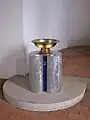 Die Taufe auf dem Sockel mit der „3“, auf den auch eine Vase gestellt werden kann