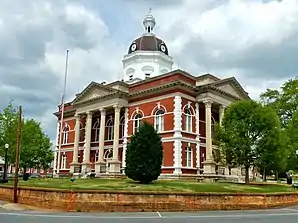 Meriwether County Courthouse (2013). Das Courthouse entstand 1903/04 im Stil der Colonial-Revival-Architektur und ersetzte einen Vorgängerbau von 1832. Ausführender Architekt war J. W. Golucke, auf den viele Gerichts- und Verwaltungsgebäude in Georgia und Alabama zurückgehen. Im Mai 1973 wurde das Meriwether County Courthouse als zweites Objekt im County in das NRHP eingetragen.