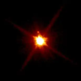 Makemake (Mitte) und sein Mond (oben) durch das Hubble-Weltraumteleskop (2015).
