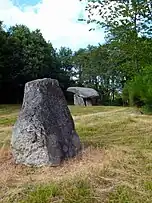 Menhir von Chez Moutaud  im Hintergrund der Dolmen