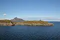 Norwegen: Polarkreiszeichen auf der kleinen Insel Vikingen, im Hintergrund die Felsformation Hestmannen