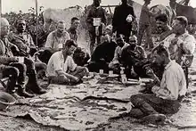 Abendessen im Lager. Von links sitzend: Pater Zahm, Colonel Rondon, Dr. Cajazeira, Kermit Roosevelt (im Schneidersitz), Miller, Cherrie, drei nicht identifizierte Brasilianer, Theodore Roosevelt, Fiala