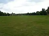 Die Stelle des Amphitheaters, das heute noch als leichte Mulde auf einer Wiese zu erkennen ist.