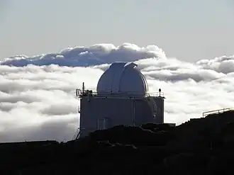 Das Jacobus-Kapteyn-Teleskop 2011 gegen Wolkenhintergrund bei aufgehender Sonne
