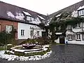 Eingang zur Brauerei mit dem Brunnen, der aus Teilen der ehemaligen Turbinenanlage besteht.