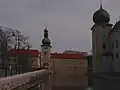 Westansicht des Wirtschaftshofes mit barockem Torturm, Zugang über erste Brücke