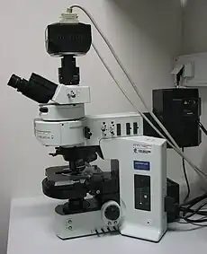 Ein aufrechtes Epifluoreszenzmikroskop. Das schwarze Gehäuse rechts enthält die Lichtquelle für die Fluoreszenz-Anregung. Im schwarzen Gehäuse oben auf dem Mikroskop befindet sich eine CCD-Kamera.
