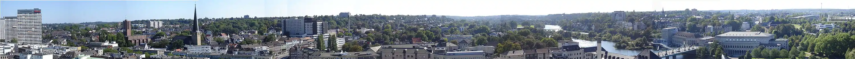 Blick vom Rathausturm - Stadtpanorama von Ost über Süd nach West: Die Kirchen links sind St. Mariae Geburt und Petrikirche auf dem Kirchenhügel. Rechts im Bild führt die Schlossbrücke von der Innenstadt auf die linke Ruhrseite, dort liegen direkt an der Brücke das Hauptgebäude des Rheinisch-Westfälischen Wasserwerks und die Stadthalle, hinter der Stadthalle ist hinter Bäumen versteckt das Schloss Broich. Ganz rechts außen ist die Heinrich-Thöne-Volkshochschule.