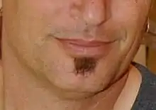 A close-up of a man's smile with a small bit of hair under his lower lip